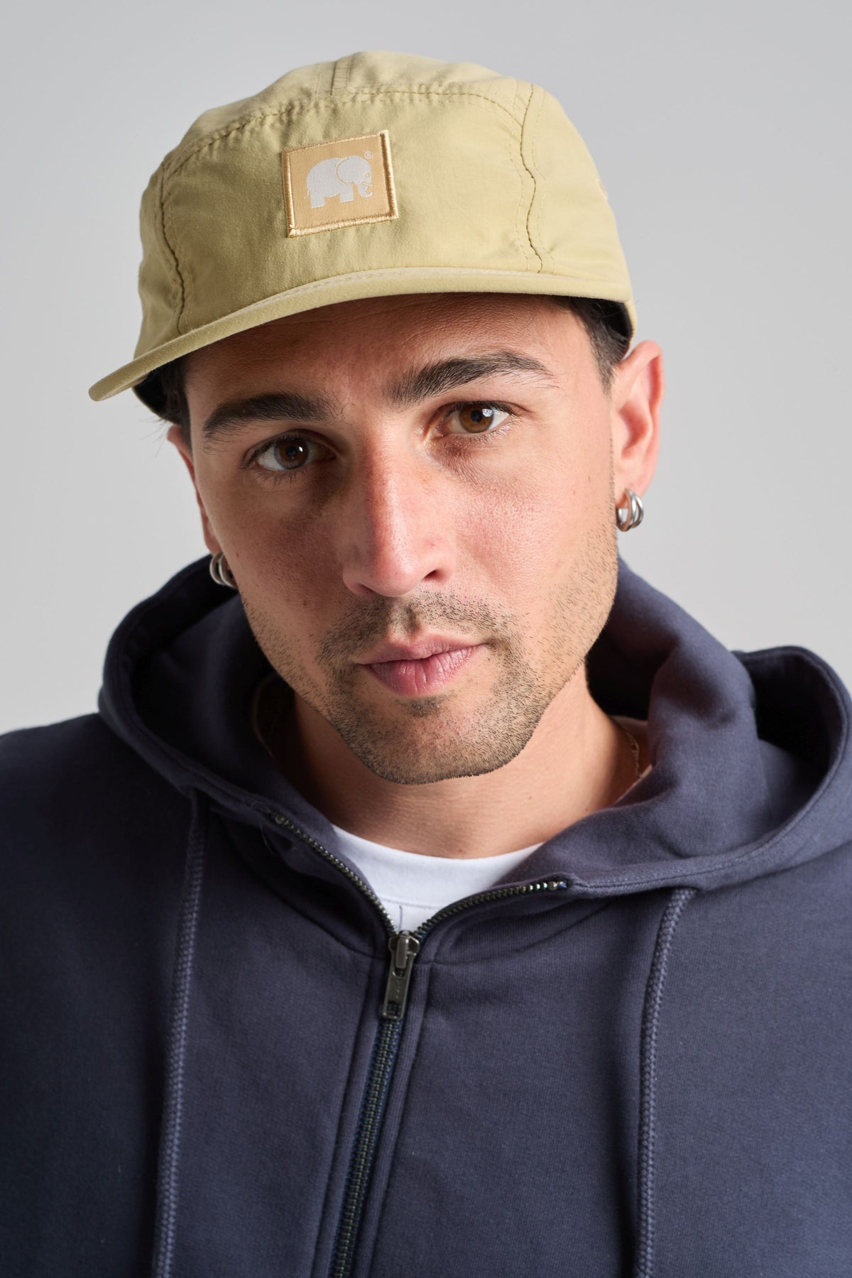 Persona che indossa un cappello a cinque pannelli in nylon idrorepellente color sabbia, vista frontale | TP_IMAGE_TYPE=MODEL_FRONT