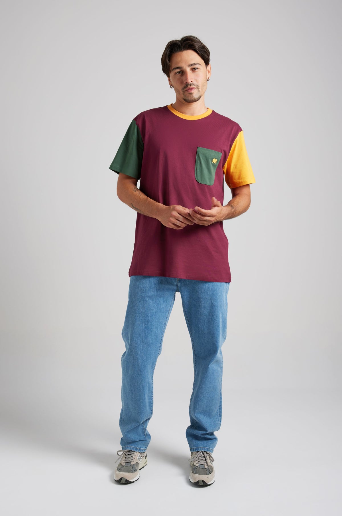 Person wearing an organic pocket color block t-shirt in burgundy with green and yellow sleeves, standing against a neutral background | TP_IMAGE_TYPE=MODEL_FRONT