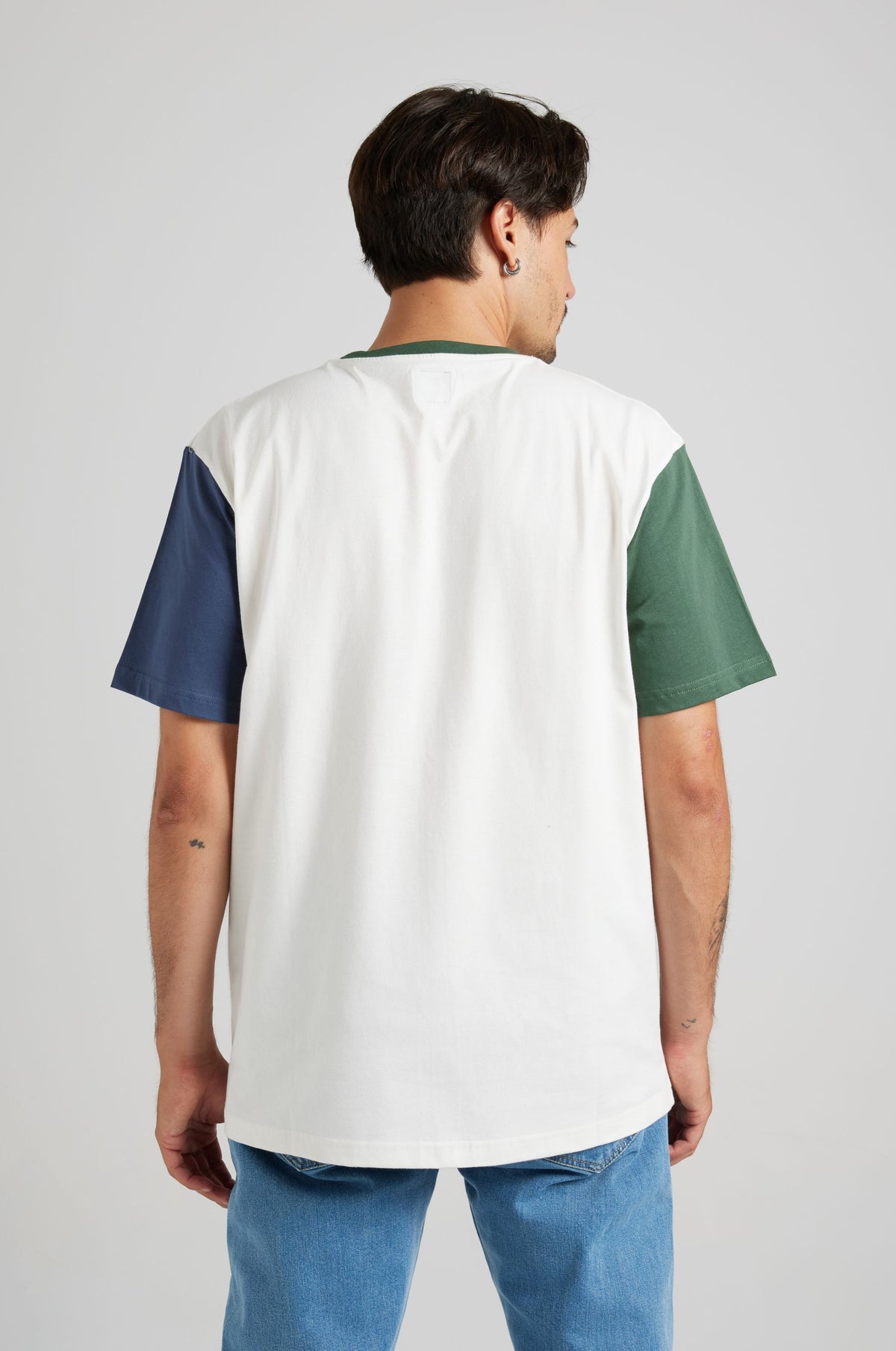 Persona che indossa una T-Shirt Organic Color Block nei colori naturali, con sezioni verde, blu navy e bianco, vista di spalle. | TP_IMAGE_TYPE=MODEL_BACK