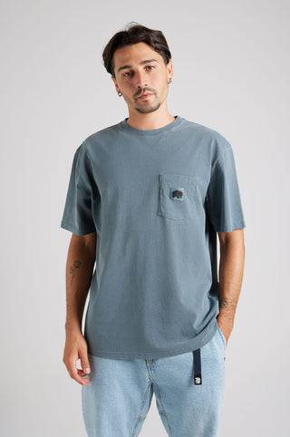 Personne portant un Garza Pigment Dyed T-Shirt en Elm Green, avec une poche poitrine et une coupe décontractée | TP_IMAGE_TYPE=MODEL_FRONT