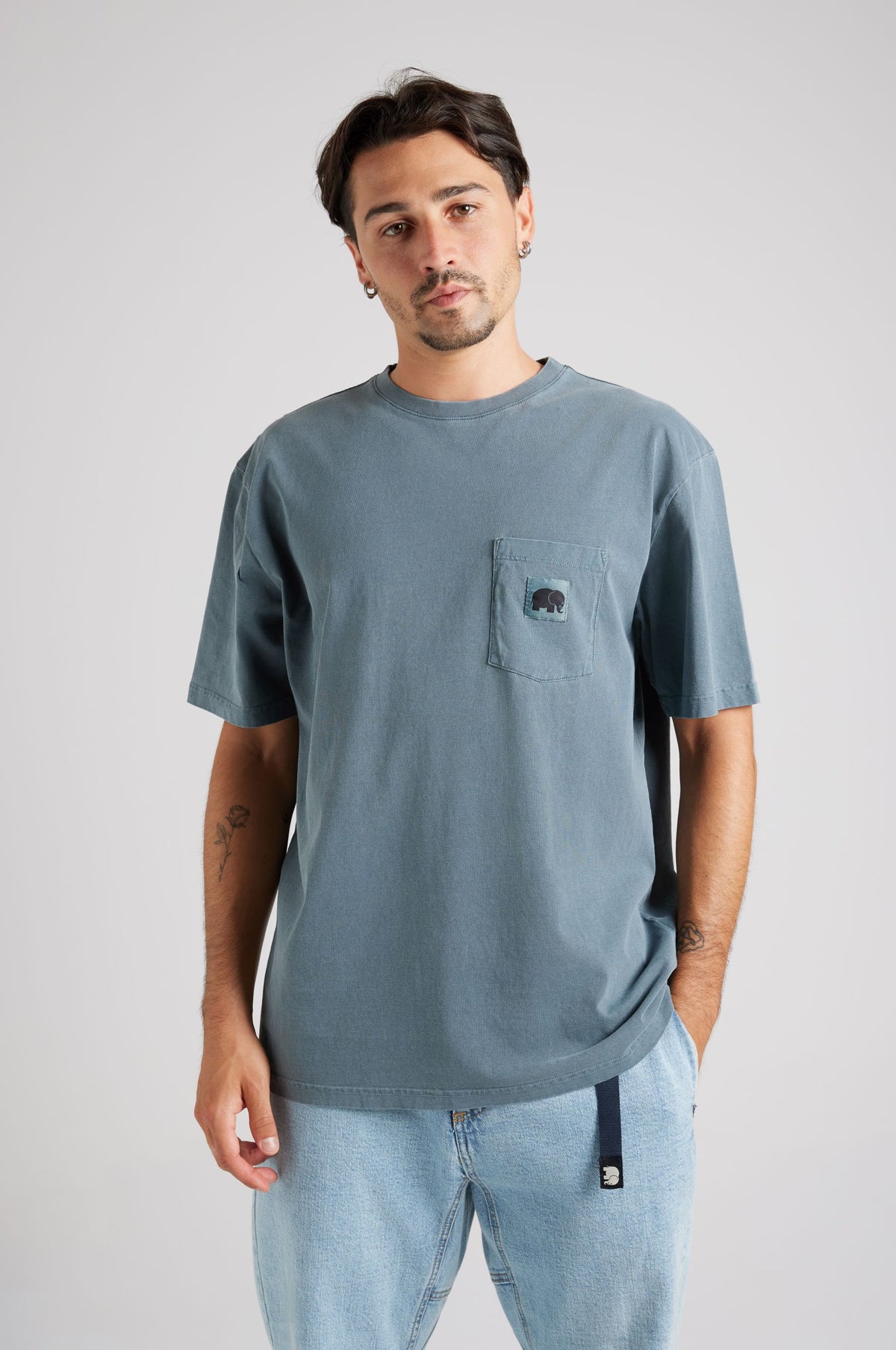 Personne portant un Garza Pigment Dyed T-Shirt en Elm Green, avec une poche poitrine et une coupe décontractée | TP_IMAGE_TYPE=MODEL_FRONT