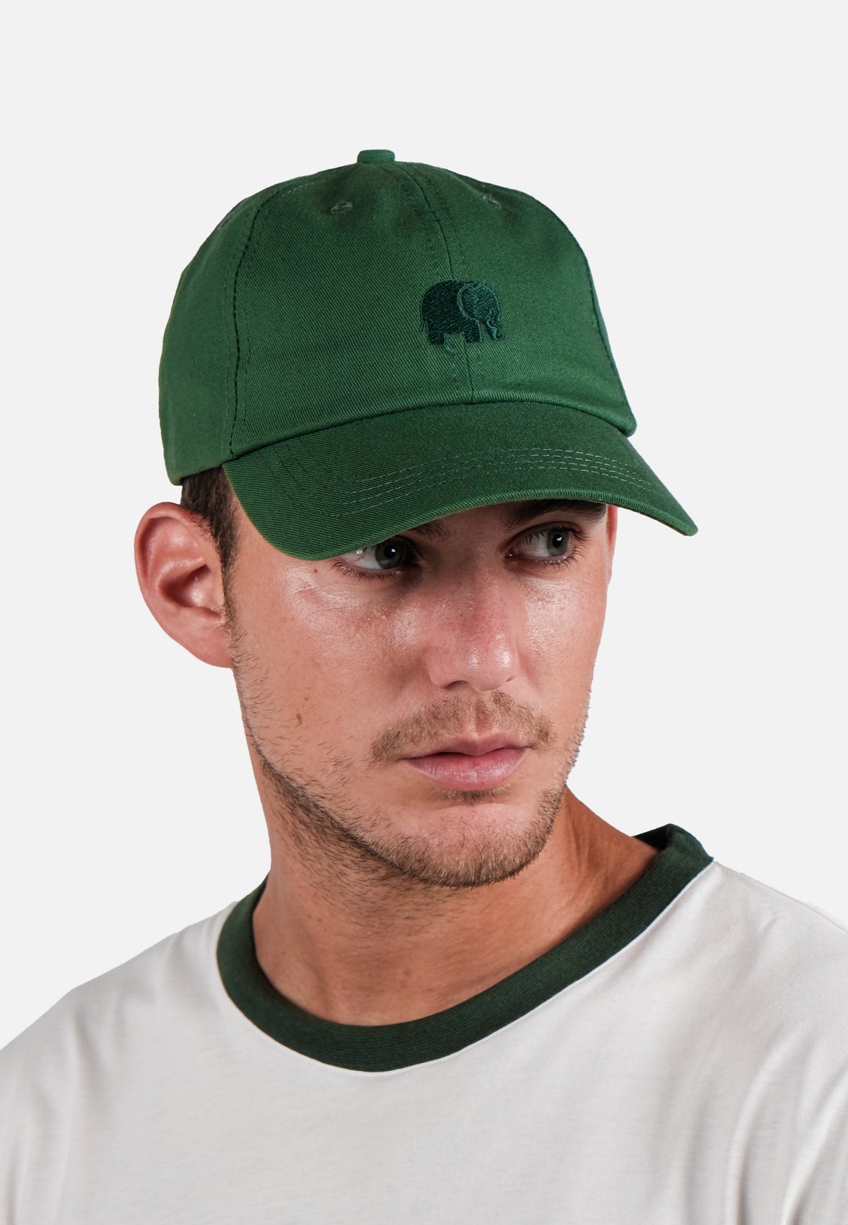 Persona che indossa un dad cap con logo verde muschio, caratterizzato da un logo ricamato, abbinato a una camicia bianca con colletto verde | TP_IMAGE_TYPE=MODEL_FRONT
