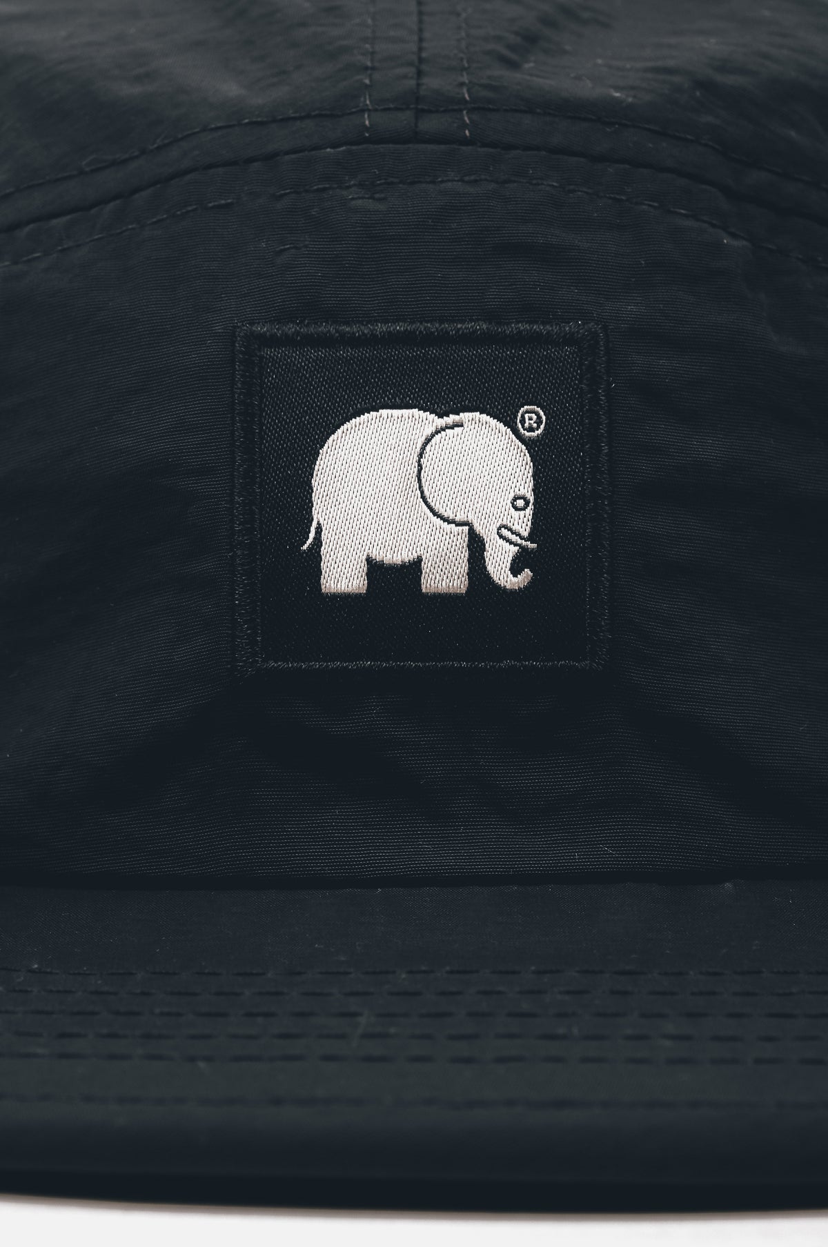 Dettaglio ravvicinato del Water Repellent Nylon Five Panel Cap in nero che mostra la patch con il logo | TP_IMAGE_TYPE=DETAIL