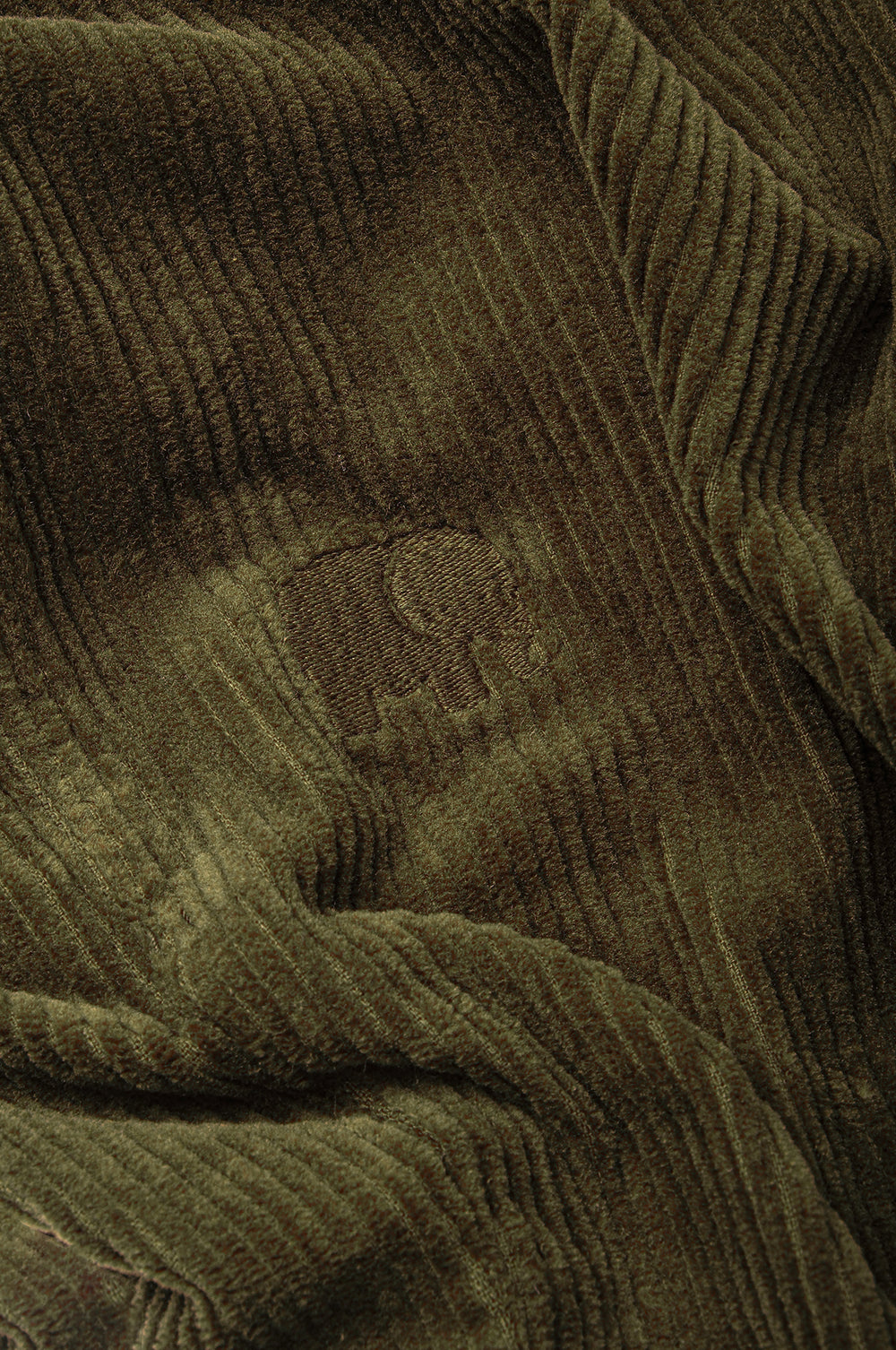 Dettaglio ravvicinato del tessuto in velluto a coste Dark Olive che mostra la texture e il logo | TP_IMAGE_TYPE=DETAIL