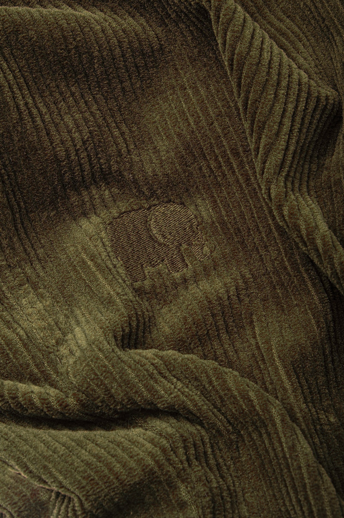 Dettaglio ravvicinato del tessuto in velluto a coste Dark Olive che mostra la texture e il logo | TP_IMAGE_TYPE=DETAIL