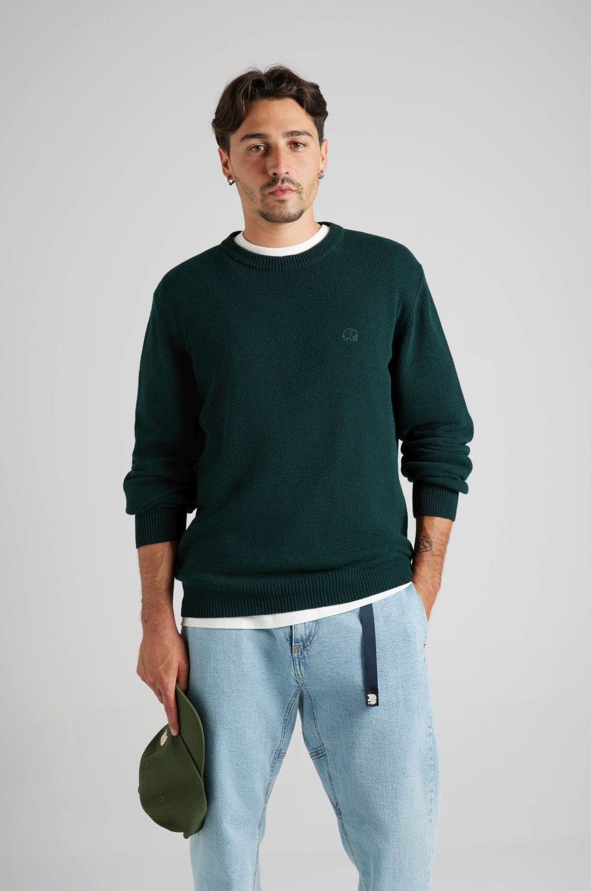 Persona che indossa un maglione Tarbena Knit verde pino con vestibilità morbida e polsini a coste, con un cappello in mano | TP_IMAGE_TYPE=MODEL_FRONT