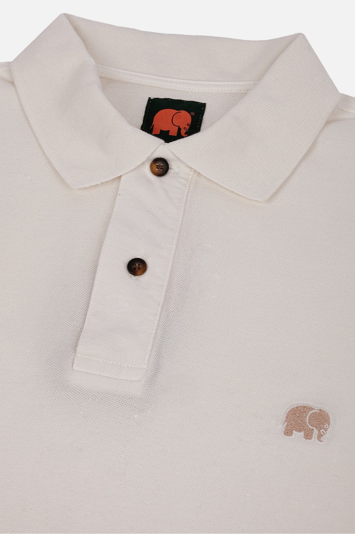 Dettaglio in primo piano della Alcalali Pigment Dyed Organic Polo Shirt in Almond Milk, che mostra il colletto, i bottoni e il logo elefante ricamato. | TP_IMAGE_TYPE=DETAIL