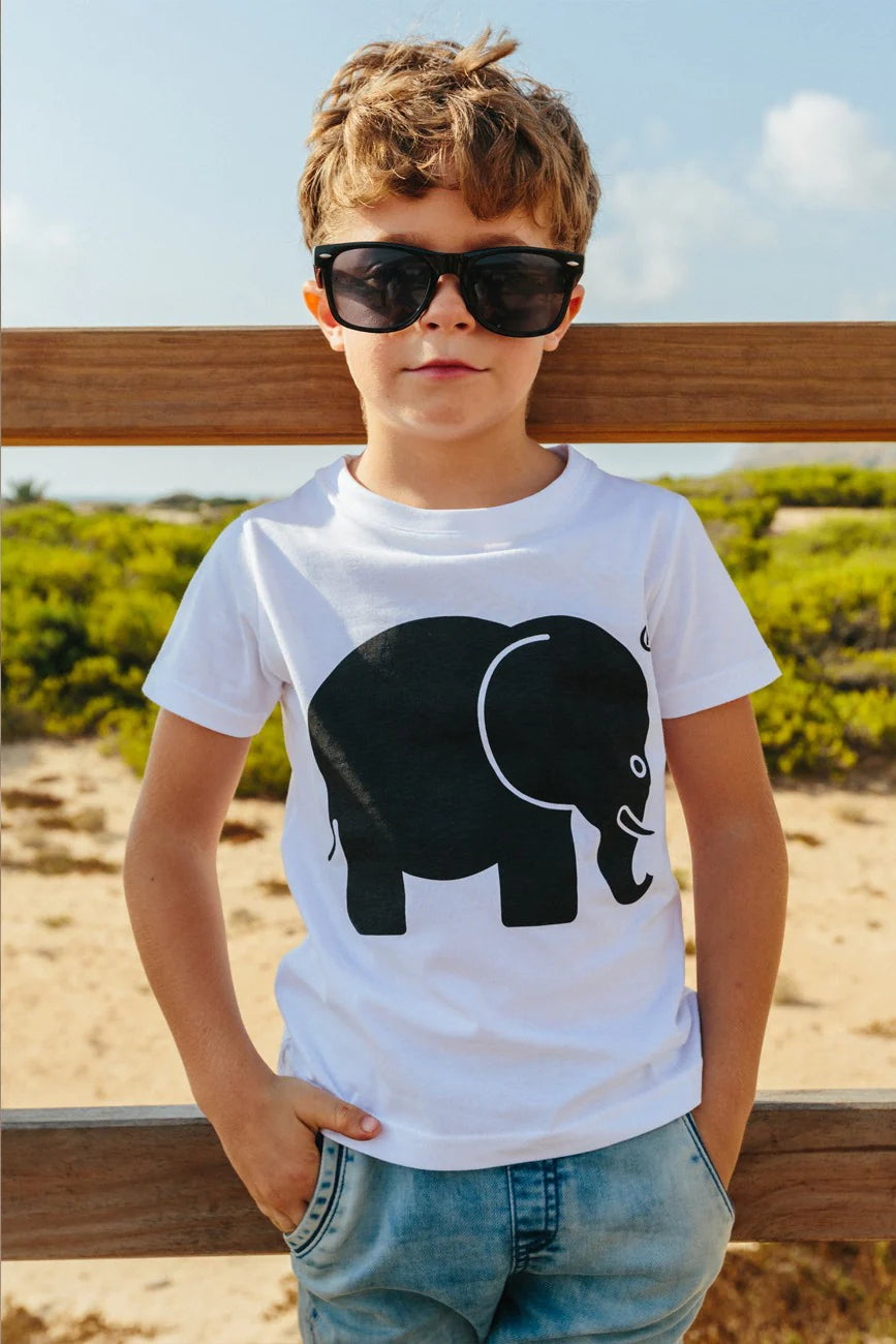 Persona che indossa una t-shirt classica biologica bianca con una grafica di un elefante nero, in piedi all'aperto con uno sfondo naturale. | TP_IMAGE_TYPE=MODEL_FRONT