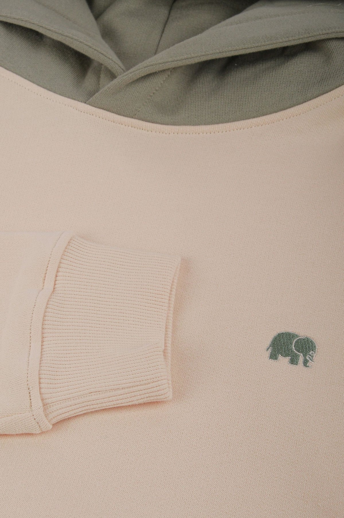 Close-up detail of Color Block Hoodie in Pale Glow showing the soft fabric and green elephant logo | TP_IMAGE_TYPE=DETAIL
