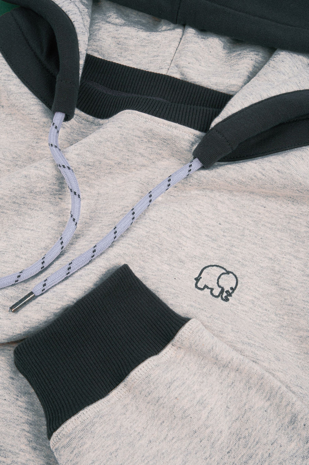 Détail en gros plan du The Hooded Oversized Sweatshirt en Warm Heather Grey/Scarab, mettant en valeur le tissu, le logo et le cordon de serrage | TP_IMAGE_TYPE=DETAIL