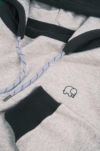Détail en gros plan du The Hooded Oversized Sweatshirt en Warm Heather Grey/Scarab, mettant en valeur le tissu, le logo et le cordon de serrage | TP_IMAGE_TYPE=DETAIL