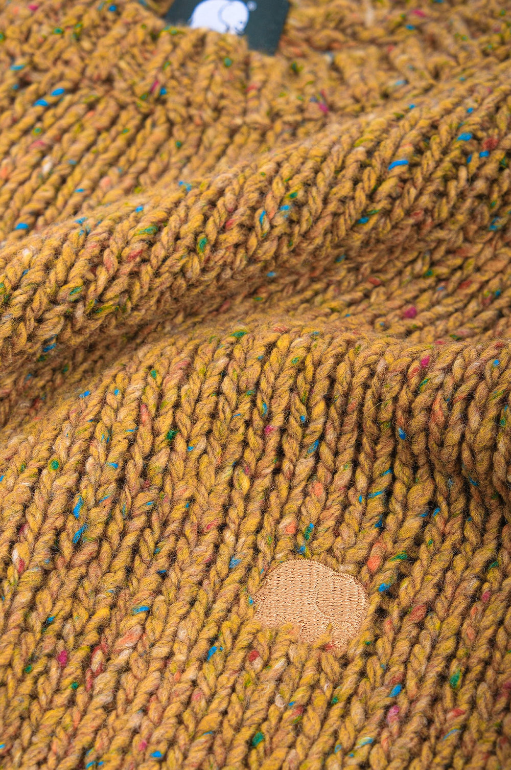 Close-up detail of the Maigmo Knit in Dijon color showcasing the textured knit and patch design. | TP_IMAGE_TYPE=DETAIL