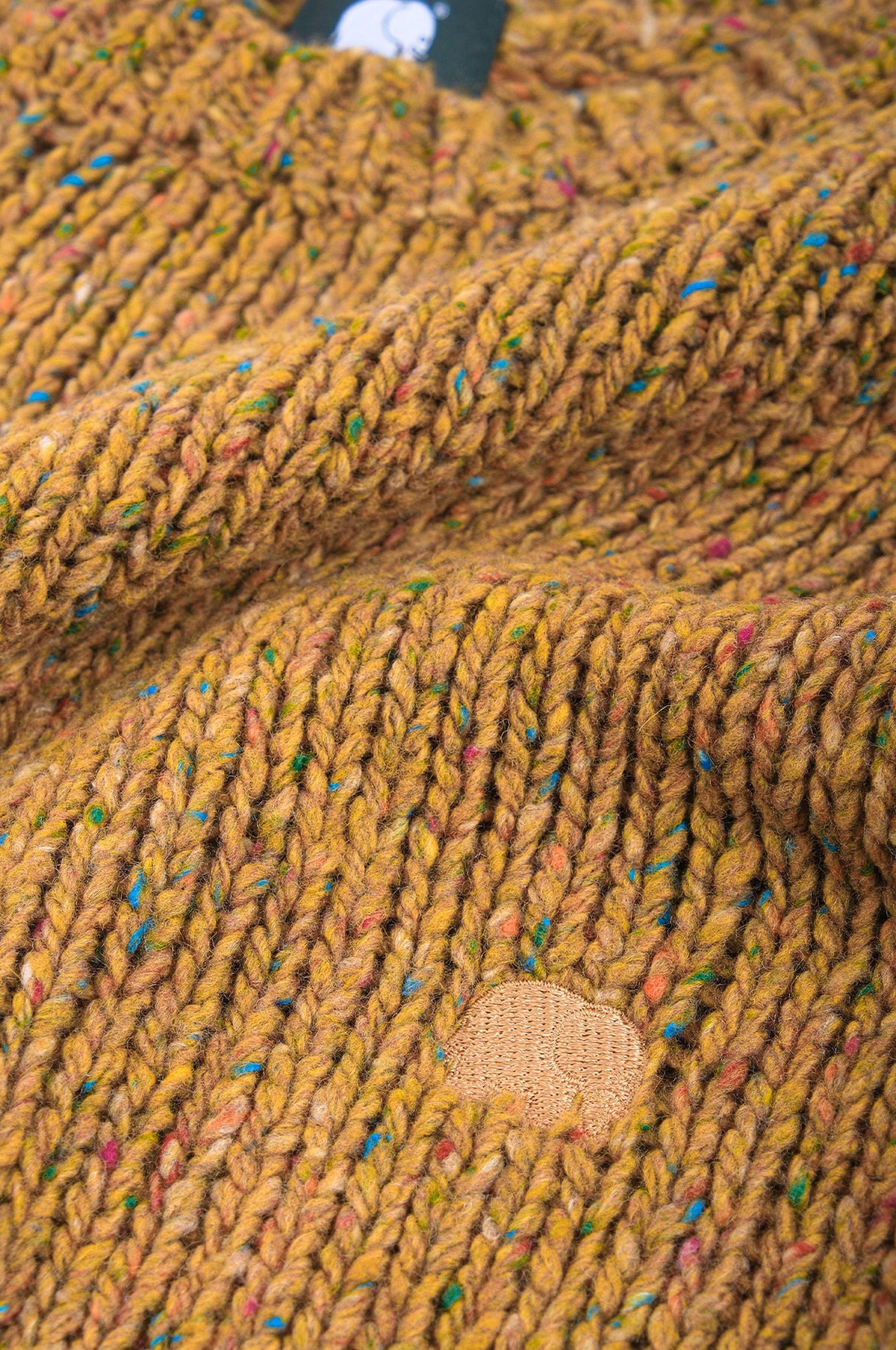 Close-up detail of the Maigmo Knit in Dijon color showcasing the textured knit and patch design. | TP_IMAGE_TYPE=DETAIL