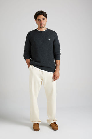 Persona che indossa un maglione Tarbena Knit Charcoal con un outfit casual, in piedi su uno sfondo neutro. | TP_IMAGE_TYPE=MODEL_FRONT