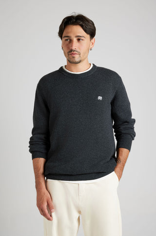 Persona che indossa il maglione Tarbena Knit Charcoal abbinato a pantaloni chiari, per un look casual e moderno. | TP_IMAGE_TYPE=MODEL_FRONT