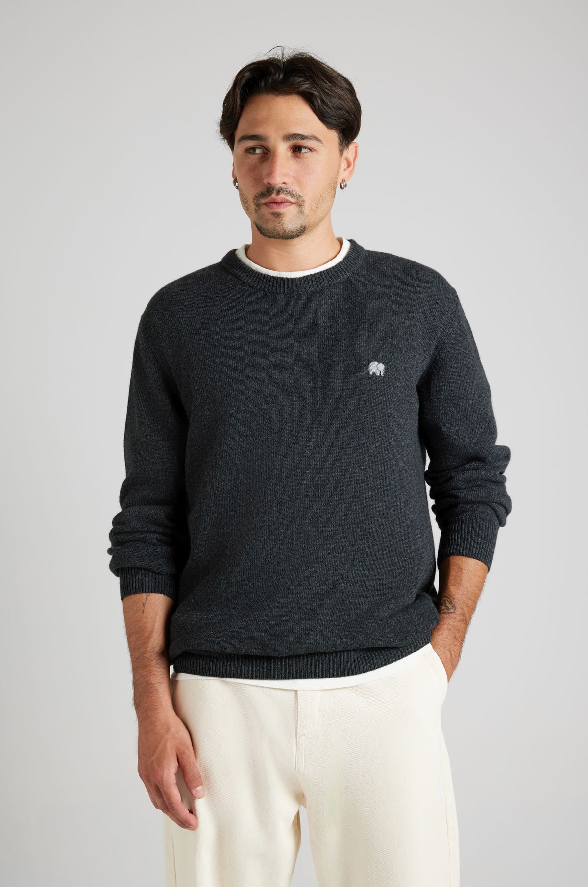 Persona che indossa il maglione Tarbena Knit Charcoal abbinato a pantaloni chiari, per un look casual e moderno. | TP_IMAGE_TYPE=MODEL_FRONT