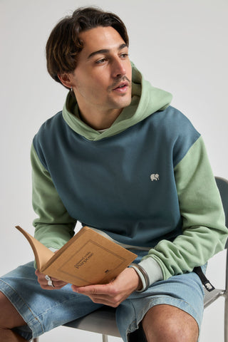 Persona che indossa una Color Block Hoodie Deep Spruce, seduta e con un libro in mano, vista frontale | TP_IMAGE_TYPE=MODEL_FRONT