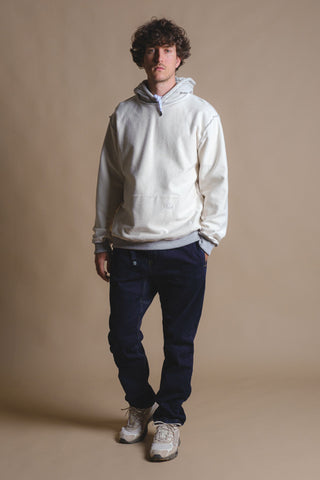 Persona che indossa una felpa con cappuccio in pile reversibile in grigio melange caldo, abbinata a pantaloni in denim scuro, in piedi su uno sfondo neutro | TP_IMAGE_TYPE=MODEL_FRONT