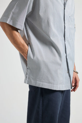 Persona che indossa una camicia a righe blu e bianche con sfondo neutro