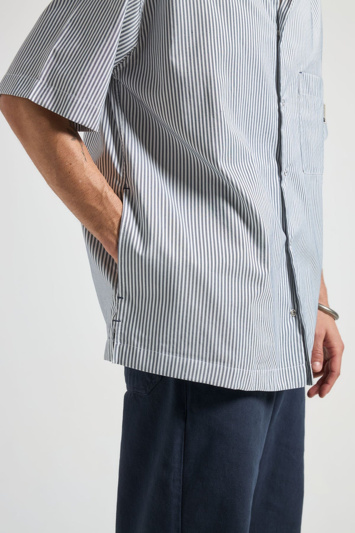 Persona che indossa una camicia a righe blu e bianche con sfondo neutro