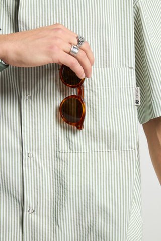 Personne portant une Mechanic Box Seaqual® Yarn S/S Shirt à rayures vertes, tenant des lunettes de soleil | TP_IMAGE_TYPE=MODEL_FRONT