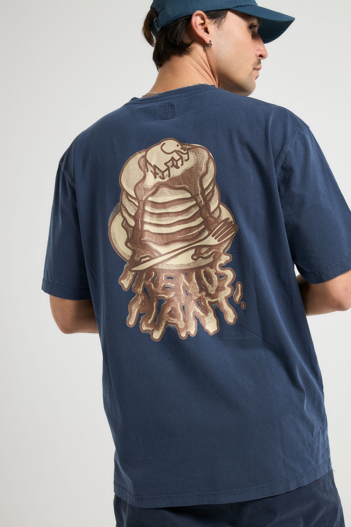 Persona che indossa una T-Shirt Panqueque in Pageant Blue, vista posteriore che mostra il design grafico dei pancake | TP_IMAGE_TYPE=MODEL_BACK