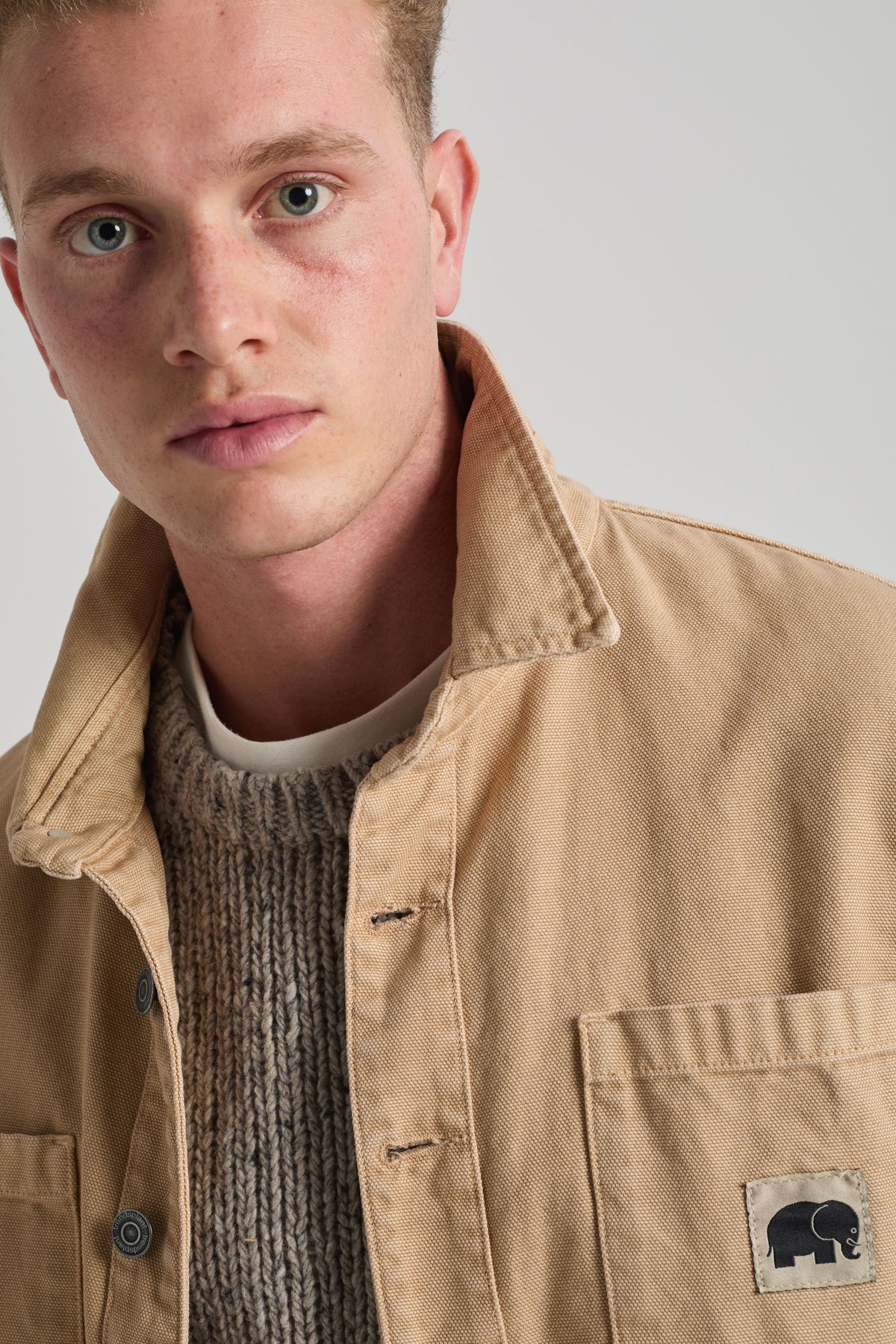 Persona che indossa una Albir Canvas Overshirt Sand con un maglione in maglia testurizzata sotto, vista frontale | TP_IMAGE_TYPE=MODEL_FRONT