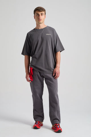 Persona che indossa Operator Relaxed Pants nel colore Forged Iron, abbinati a una t-shirt ampia e a sneakers rosse vivaci. | TP_IMAGE_TYPE=MODEL_FRONT