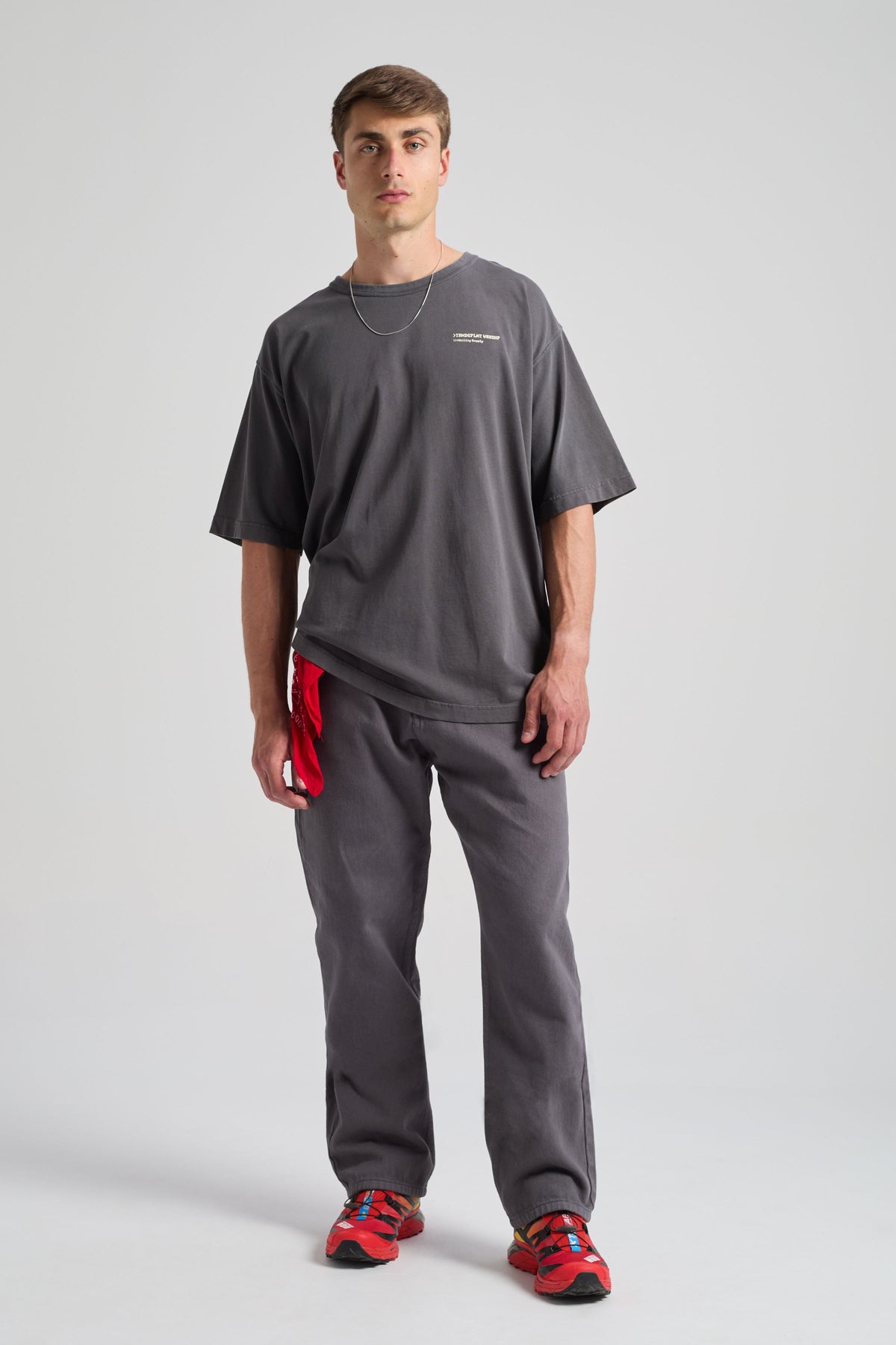 Persona che indossa Operator Relaxed Pants nel colore Forged Iron, abbinati a una t-shirt ampia e a sneakers rosse vivaci. | TP_IMAGE_TYPE=MODEL_FRONT