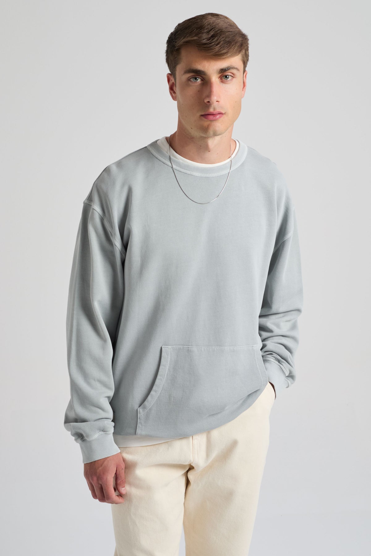 Persona che indossa una Hangar Sweatshirt Quarry Blue con tasca, abbinata a pantaloni chiari | TP_IMAGE_TYPE=MODEL_FRONT