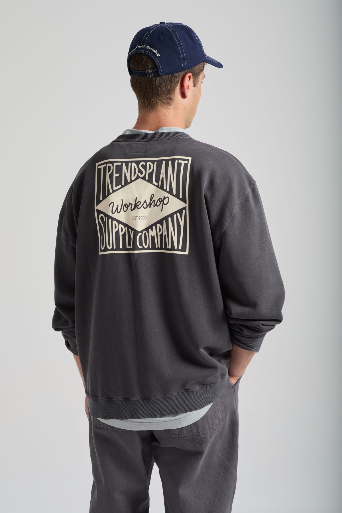 Personne portant un Factory Oversized Sweatshirt en Forged Iron, montrant le design au dos avec le logo Trendplant Workshop | TP_IMAGE_TYPE=MODEL_BACK