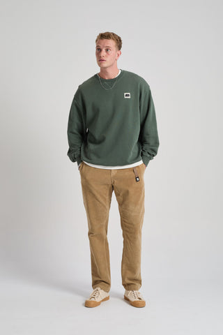 Persona che indossa una felpa verde e pantaloni marroni su sfondo bianco. TP_IMAGE_TYPE=MODEL_FRONT