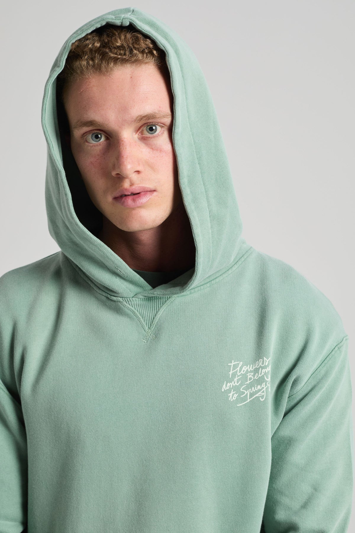 Persona che indossa una Flowers Hoodie color Vintage Sage, con cappuccio con coulisse e testo ricamato. | TP_IMAGE_TYPE=MODEL_FRONT
