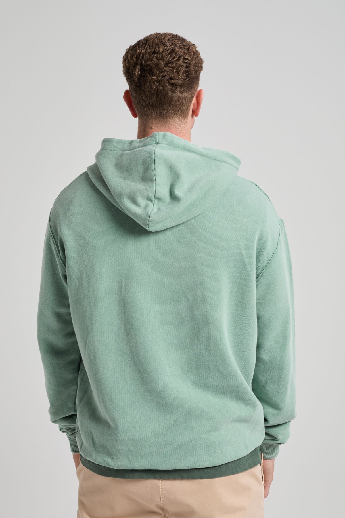 Persona che indossa una Flowers Hoodie in Vintage Sage, vista di spalle, che mette in risalto il design e il colore della hoodie. | TP_IMAGE_TYPE=MODEL_BACK