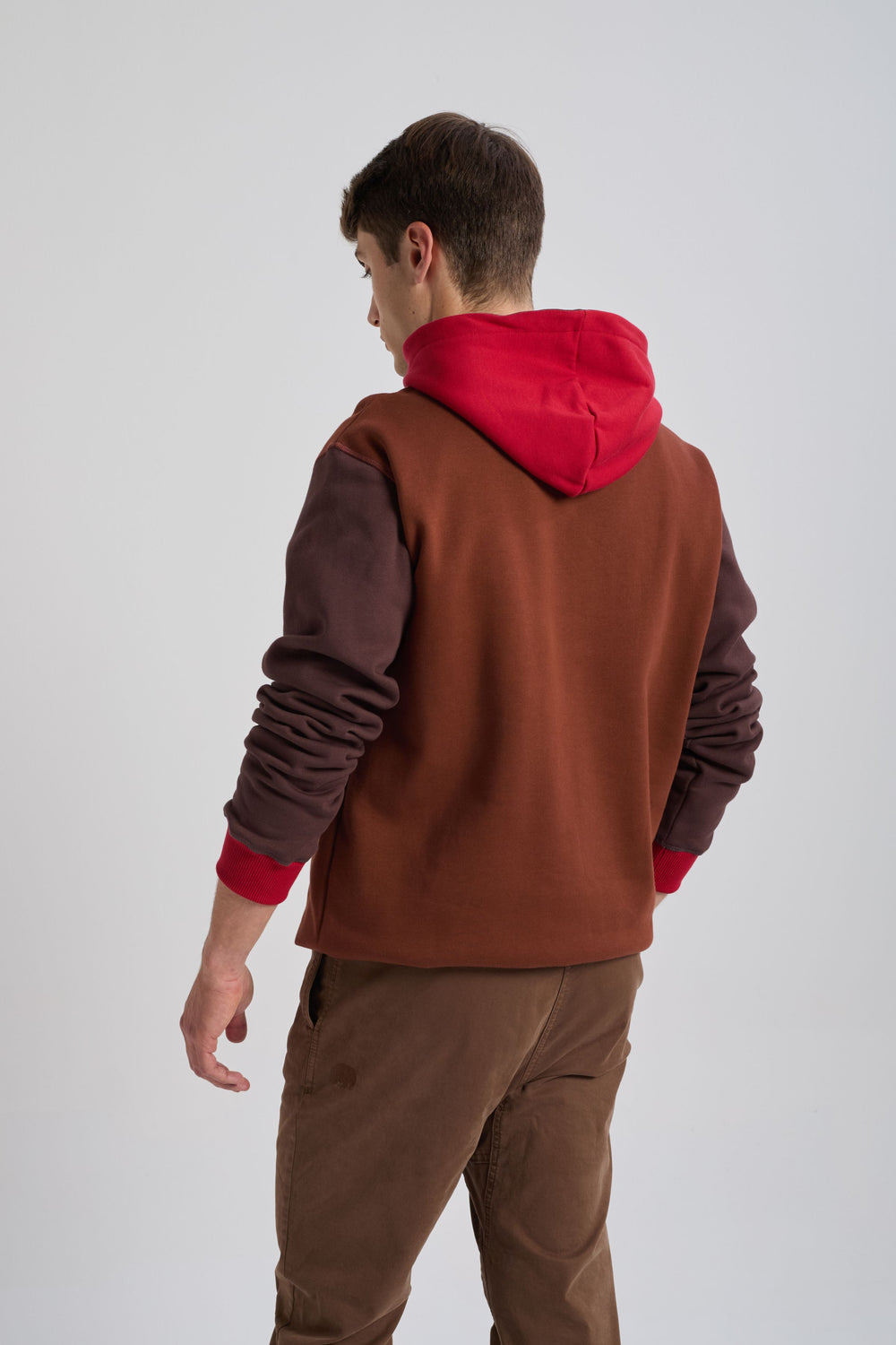 Persona che indossa una felpa con cappuccio Color Block in ciliegia e mogano, vista posteriore con cappuccio rosso e maniche marroni | TP_IMAGE_TYPE=MODEL_BACK