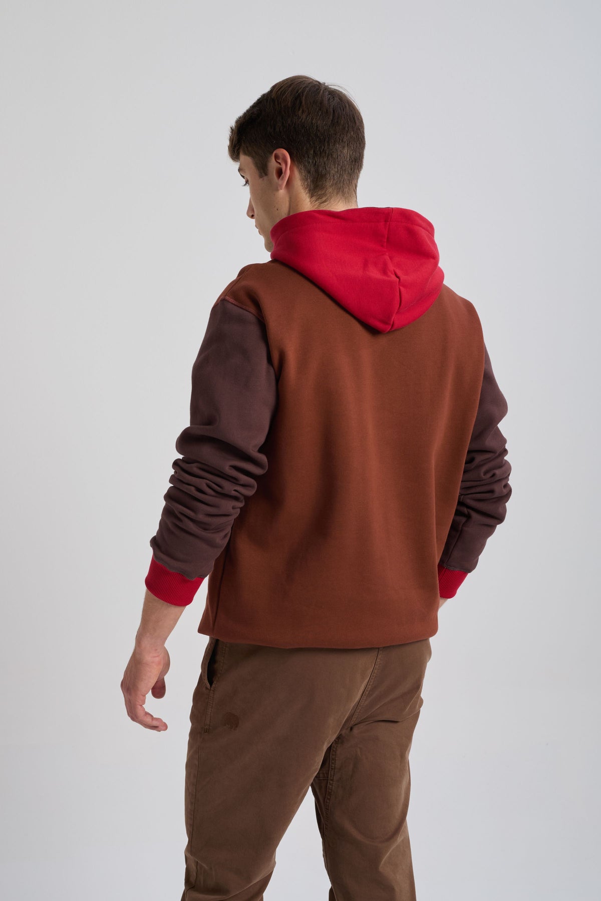 Persona che indossa una felpa con cappuccio Color Block in ciliegia e mogano, vista posteriore con cappuccio rosso e maniche marroni | TP_IMAGE_TYPE=MODEL_BACK