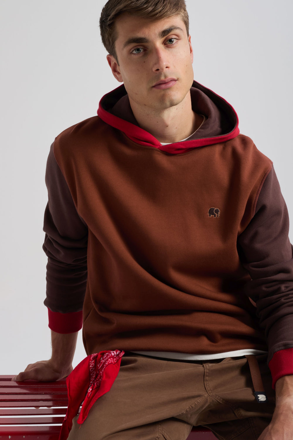 Persona che indossa una felpa Color Block in Cherry Mahogany con cappuccio rosso e corpo marrone, abbinata a una bandana rossa in vita. | TP_IMAGE_TYPE=MODEL_FRONT