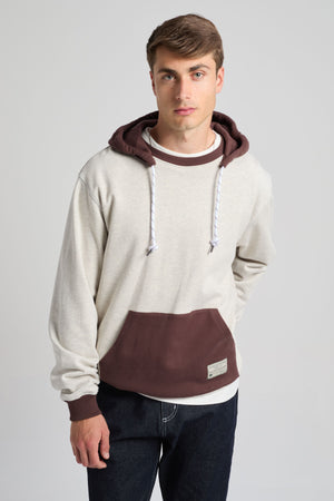 Persona che indossa una felpa oversize con cappuccio in grigio melange caldo e color caffè, con tasca frontale e cappuccio a contrasto. | TP_IMAGE_TYPE=MODEL_FRONT