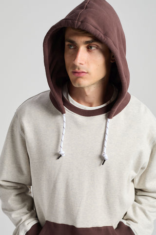 Persona che indossa The Hooded Oversized Sweatshirt in grigio mélange caldo e coffee, con cappuccio accogliente e orlo a contrasto | TP_IMAGE_TYPE=MODEL_FRONT