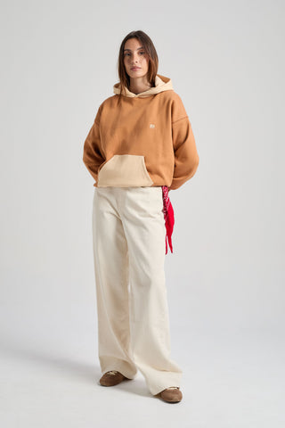 Personne portant un sweat à capuche color block en coloris cajou, avec capuche et poche beiges, associé à un pantalon large de couleur claire | TP_IMAGE_TYPE=MODEL_FRONT