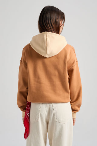 Personne portant un sweat à capuche color block pour femme de couleur noix de cajou, avec une capuche beige contrastante, stylisée avec un bandana rouge glissé dans la poche arrière d'un pantalon clair. | TP_IMAGE_TYPE=MODEL_BACK