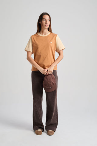 Personne portant un t-shirt Color Block dans des tons cajou, tenant un chapeau marron, avec un pantalon décontracté | TP_IMAGE_TYPE=MODEL_FRONT