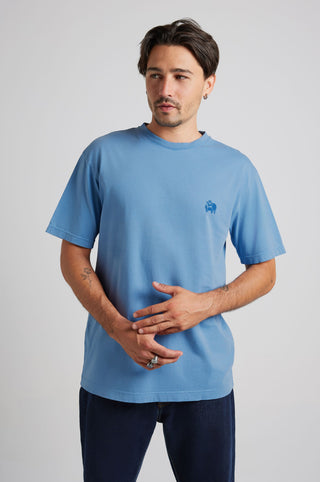 Person wearing a blue short-sleeved T-shirt with a small chest graphic, looking to the side | TP_IMAGE_TYPE=MODEL_FRONT