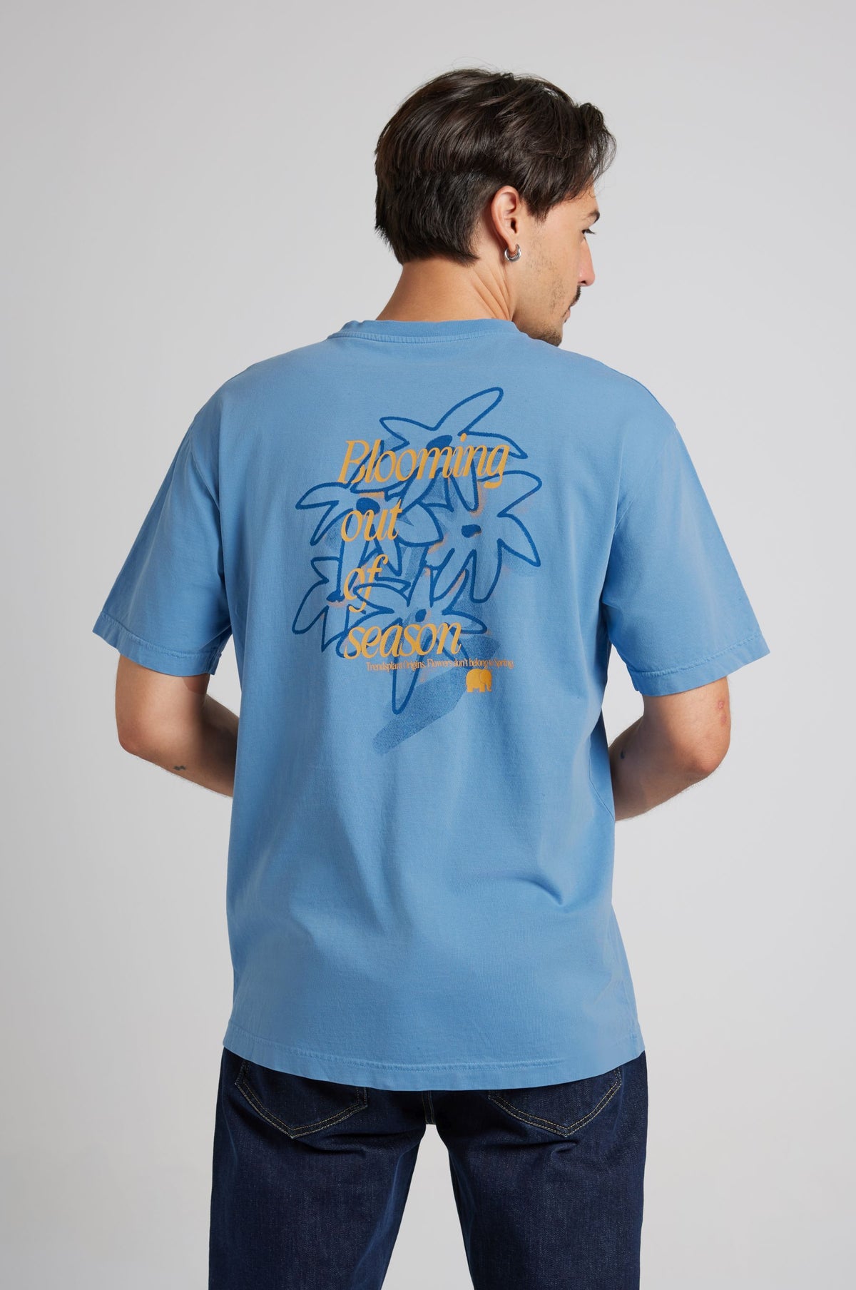 Person wearing a blue short-sleeved T-shirt with a floral graphic on the back | TP_IMAGE_TYPE=MODEL_BACK