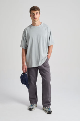 Personne portant un t-shirt Worldwide Sunwashed Heavy Oversized en Quarry Blue, debout et tenant un chapeau. | TP_IMAGE_TYPE=MODEL_FRONT