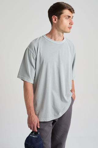 Personne portant un T-shirt oversize épais bleu quarry, tenant une casquette bleu marine, présentée sur un fond neutre | TP_IMAGE_TYPE=MODEL_FRONT