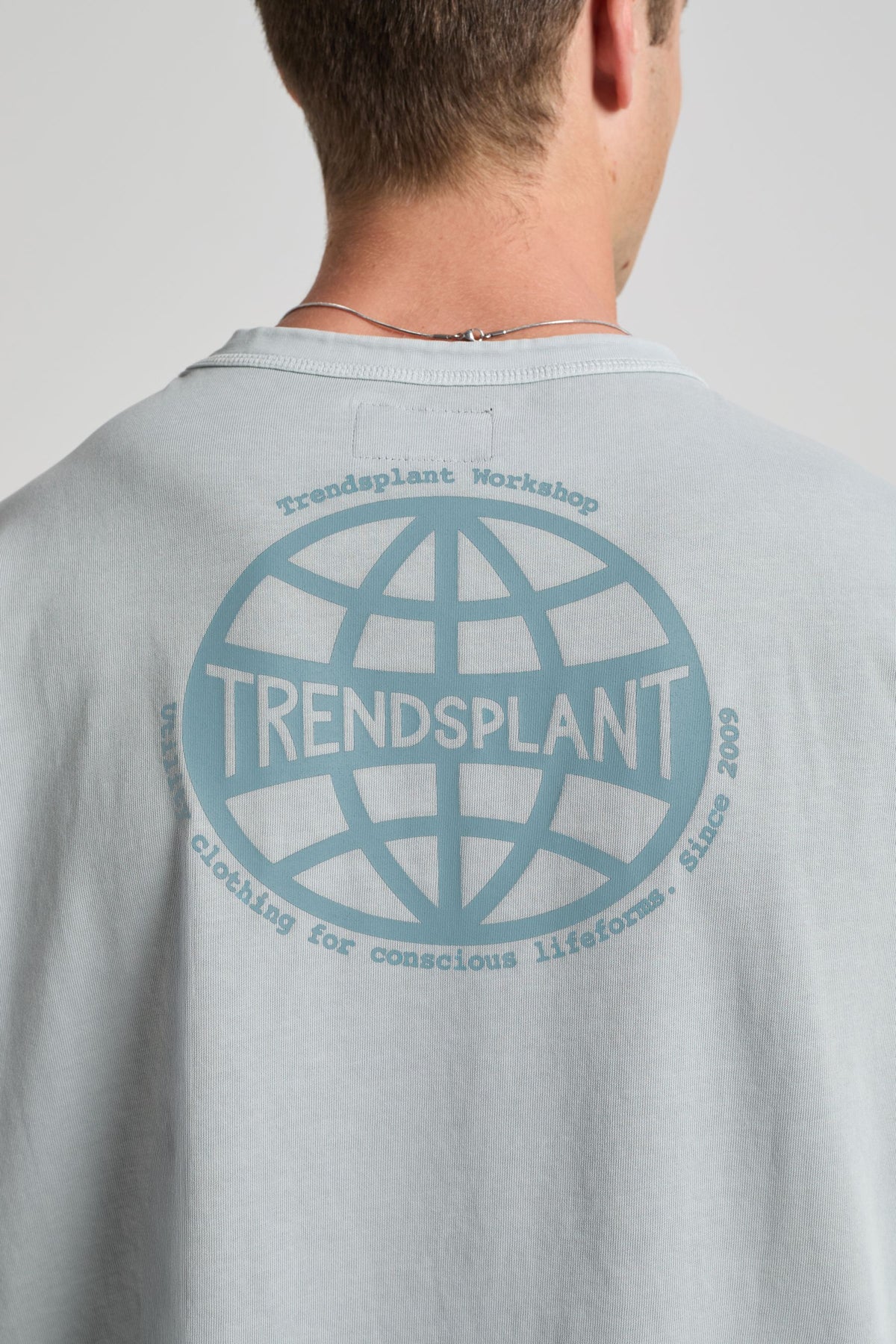 Personne portant un T-shirt Worldwide Sunwashed Heavy Oversized quarry blue avec un design graphique au dos. | TP_IMAGE_TYPE=MODEL_BACK