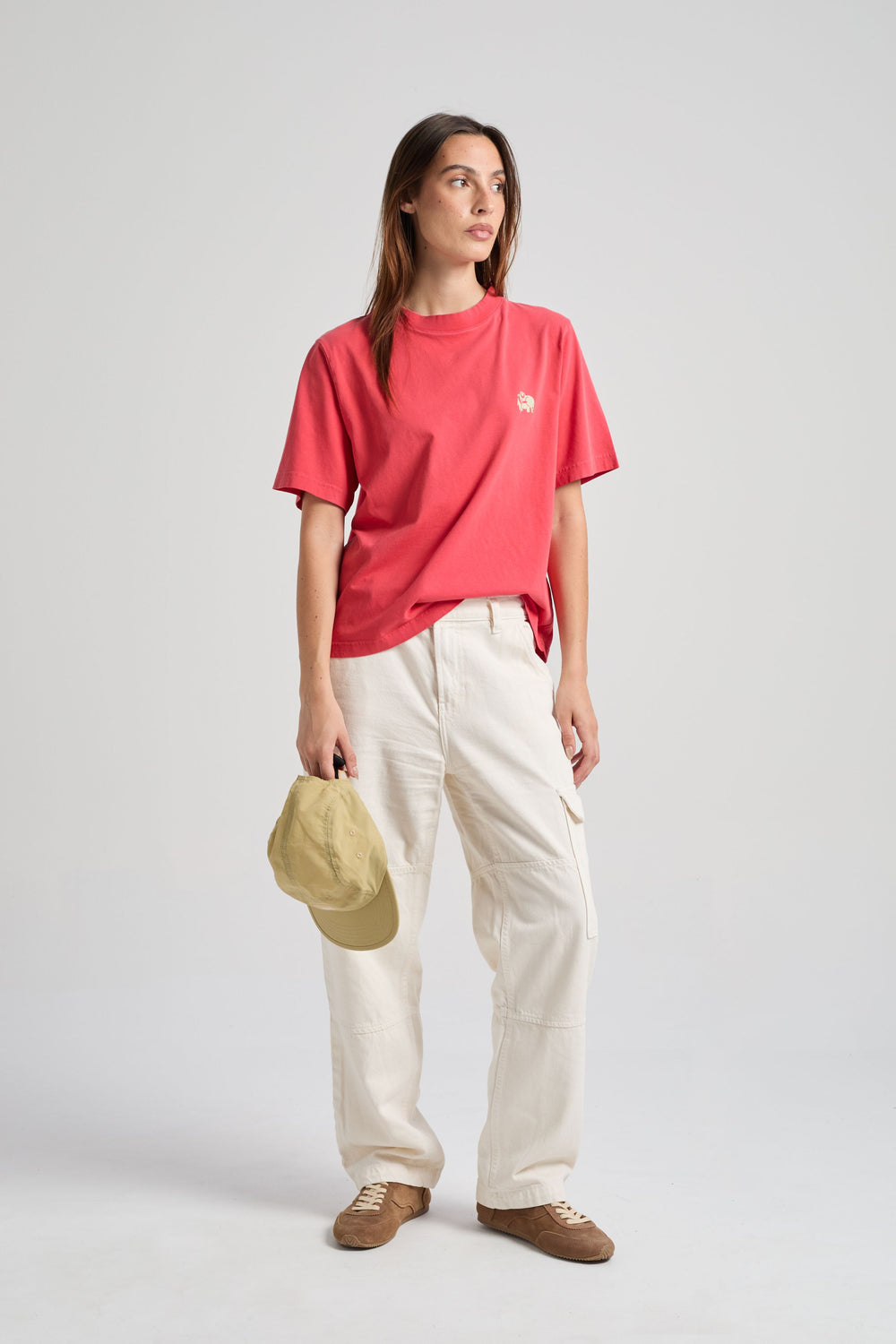 Persona che indossa una Women’s Bloom T-Shirt in Poppy Red, in posa sicura con un cappello in mano e abbinata a pantaloni chiari. | TP_IMAGE_TYPE=MODEL_FRONT