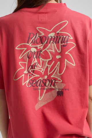 Persona che indossa una Poppy Red Women’s Bloom T-Shirt con stampa floreale e la scritta "Blooming out of season" sul retro, vista da dietro | TP_IMAGE_TYPE=MODEL_BACK
