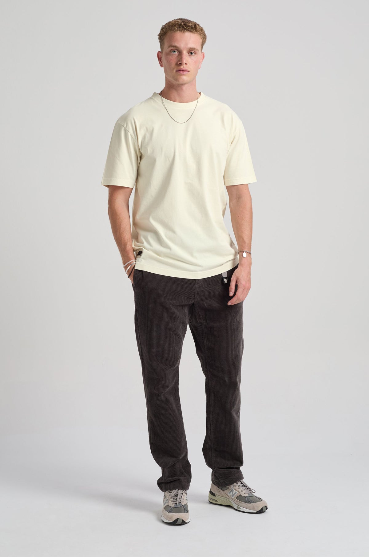 Persona che indossa la Amapola T-Shirt in Antique White, abbinata a pantaloni scuri, in posa sicura su uno sfondo neutro. | TP_IMAGE_TYPE=MODEL_FRONT